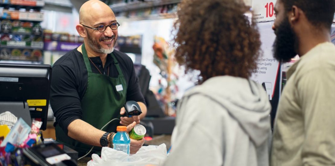 A couple shopping at a store, checking out with a cashier.